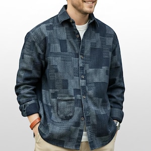 Peut inclure: Une chemise à manches longues boutonnée, avec un motif patchwork dans différentes nuances de bleu. La chemise a une poche unique sur le côté gauche et un col classique. Le tissu semble être un denim texturé ou similaire.