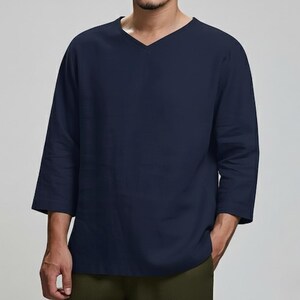 May include: Navy blue long-sleeve shirt with a V-neck design. The shirt has three-quarter sleeves and a relaxed fit. The shirt is made of a soft, comfortable material.