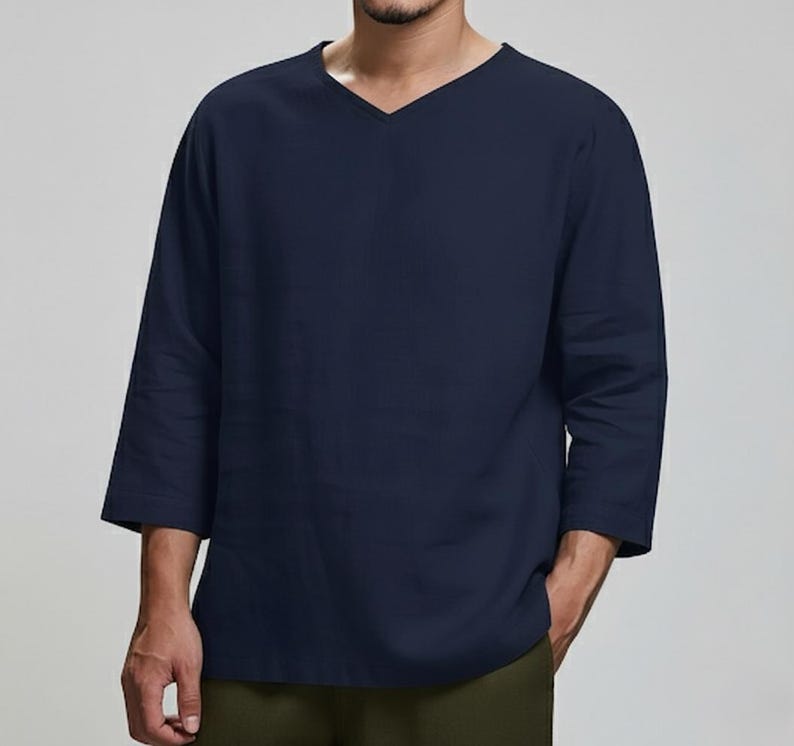 May include: Navy blue long-sleeve shirt with a V-neck design. The shirt has three-quarter sleeves and a relaxed fit. The shirt is made of a soft, comfortable material.