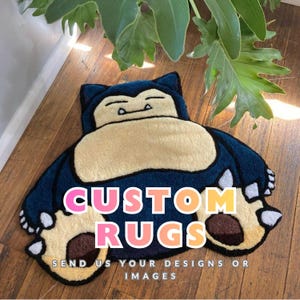 May include: A custom rug shaped like a cartoon character, with a navy blue body, beige belly, and tan paws. The rug displays the text "CUSTOM RUGS" in pink, orange, and yellow, with the text "SEND US YOUR DESIGNS OR IMAGES" below.
