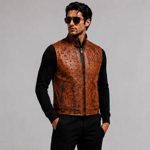 Può includere: Un gilet marrone senza maniche con motivo in pelle di struzzo testurizzata, collo alto e cerniera frontale nera a tutta lunghezza. Il capo è indossato sopra una maglia nera a maniche lunghe con pantaloni neri e occhiali da sole scuri.