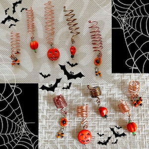 May include: A collection of copper-colored hair coils with Halloween-themed charms. The charms include orange pumpkins, red beads, and small sunflowers. Black bat silhouettes are scattered around the coils, creating a festive, seasonal look.