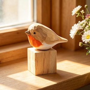 May include: A hand-carved wooden bird figurine featuring a light brown body, a bright orange chest, and a white belly, perched atop a solid, square wooden block base. The bird has visible carved facets and a small, dark, circular eye.