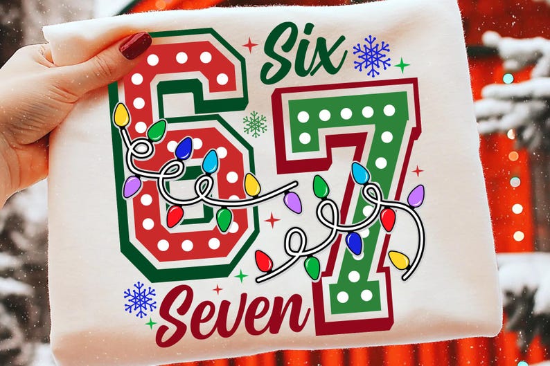 May include: A white t-shirt with a festive design featuring the words "Six" and "Seven" in green and red, with a string of colorful Christmas lights. The numbers "67" are also displayed.