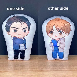 May include: Two plush pillows with cartoon illustrations. One side features a character with black hair and a blue jacket, the other side shows a character with brown hair and a blue outfit. The text "one side" and "other side" are above each pillow.