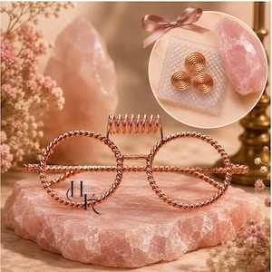 May include: Decorative glasses crafted from twisted copper-colored wire, featuring a bridge adorned with a small rose quartz crystal. A circular inset shows three copper wire spirals and a raw rose quartz stone, accented by a small pink ribbon.