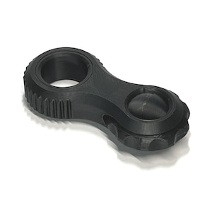 May include: A black, 3D-printed tool with a unique shape. It features a large circular opening on one end, a smaller circular indentation on the other, and a textured grip in the middle. The tool is designed for a specific purpose.