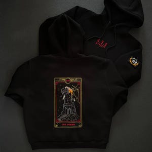 May include: Two black hooded sweatshirts. One has red text reading "4.5.0 project" and a patch. The other displays a tarot card design on the back with the words "THE TOWER".