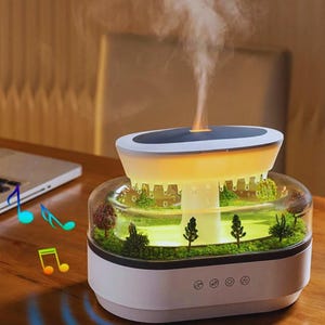 May include: A white and clear essential oil diffuser with a miniature landscape inside. The diffuser has a glowing light and emits a stream of vapor. Decorative musical notes are shown in the image.