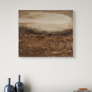 Puede incluir: Una pieza de arte mural rectangular que presenta una pintura de paisaje abstracta con capas texturizadas de pintura marrón, bronceada y crema. La composición muestra un primer plano oscuro y terroso que se transforma en un cielo claro y brumoso.
