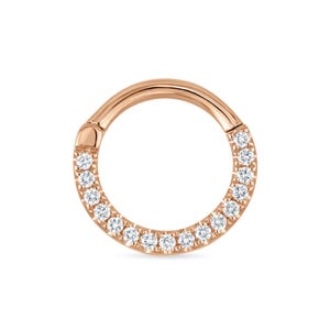 May include: Rose gold hinged hoop earring with a row of small, clear gemstones. The earring is circular and has a clasp closure. The gemstones are evenly spaced around the front of the hoop.