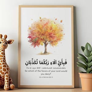 May include: A framed art print featuring a watercolor tree with autumn colors. The print includes Arabic calligraphy and English translation: "So which of the favors of your Lord would you deny?" A giraffe plush toy and potted plant are also visible.