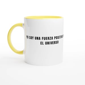 May include: White ceramic mug with a yellow interior and handle. The mug features the text "YO SOY UNA FUERZA POSITIVA EL UNIVERSO" in black. The mug is designed for hot or cold beverages.