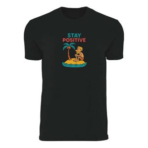 May include: Black t-shirt with a colorful graphic. The graphic features a cartoon person sitting on a small island with a palm tree. The words "STAY POSITIVE" are above the island scene.
