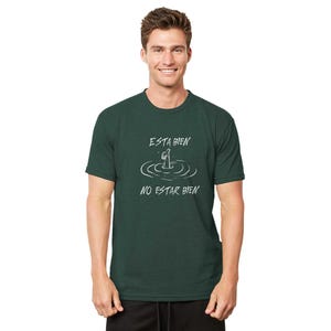 May include: Dark green t-shirt with the text "ESTA BIEN NO ESTAR BIEN" in white. The graphic depicts a person in water. The shirt is made of a soft material and has a crew neck.