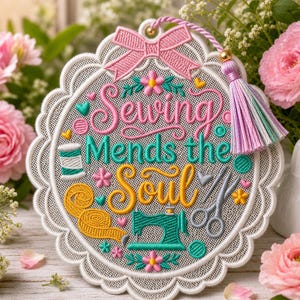 Może przedstawiać: Haftowany obraz na ścianę z napisem "Sewing Mends the Soul". Projekt zawiera różową kokardę, frędzel i obrazy związane z szyciem, takie jak maszyna do szycia, nożyczki i szpula nici. Obramowanie jest ząbkowane.