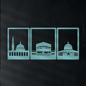May include: Three turquoise metal wall art pieces depicting Islamic landmarks. The art features cut-out silhouettes of a mosque with a minaret, the Kaaba, and a domed structure. The artwork is displayed on a dark wall above a sofa with teal cushions.
