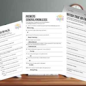 May include: Three white quiz sheets with the word "Answers" and "Quiz" printed on them. The sheets are titled "History True or False", "General Knowledge", and "British True or False". The sheets are on a wooden desk.