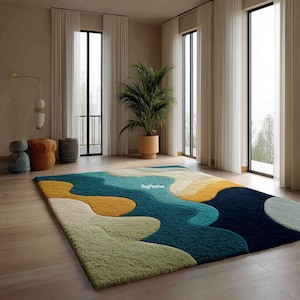 Könnte beinhalten: Ein großer, rechteckiger Teppich mit einem abstrakten Design in Grün-, Gelb-, Türkis- und Marineblautönen. Der Teppich hat ein fließendes Muster und den Text "RugFestive". Er liegt auf einem hellen Holzboden.