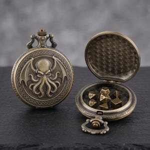 May include: Antique bronze pocket watch with an engraved Cthulhu design. The watch is open, revealing a set of gold polyhedral dice. The watch has a detailed, ornate design and a hinged lid. The watch is a unique item for tabletop gaming.