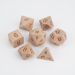 Puede incluir: Juego de siete dados poliédricos de madera clara con números grabados. El conjunto incluye un dado de cuatro caras, un dado de seis caras, un dado de ocho caras, un dado de diez caras, un dado de doce caras, un dado de veinte caras y un dado de porcentaje.