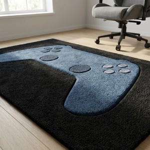 Peut inclure: Un tapis rectangulaire noir avec un motif de manette de jeu vidéo bleue. La manette comporte des boutons et des pavés directionnels. Le tapis est posé sur un parquet près d'une fenêtre et d'une chaise de bureau grise.