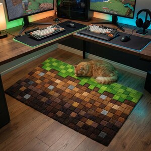 May include: A rectangular rug with a pixelated design, resembling a Minecraft block of dirt and grass. The rug is brown and green, with a fluffy orange cat resting on it. The rug is placed on a wooden floor.
