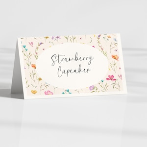 May include: A folded card with a floral design and the words "Strawberry Cupcakes" in elegant script. The card features a cream background with colorful flowers and greenery, perfect for a dessert table.