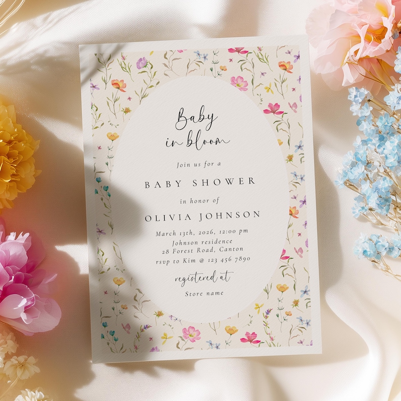 Może przedstawiać: Zaproszenie na baby shower z kwiatowym wzorem. Zaproszenie zawiera tekst "Baby in bloom" oraz szczeg&oacute;ły dotyczące wydarzenia, w tym imię honorowanej osoby, datę, godzinę i miejsce. Zaproszenie jest ozdobione kolorowymi kwiatami.
