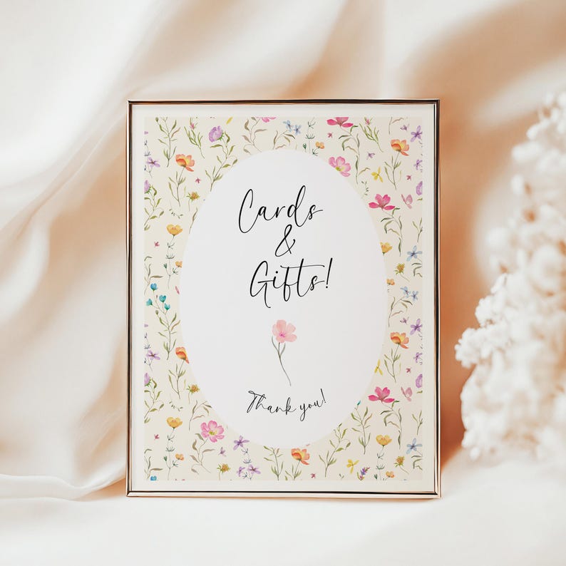 May include: A framed sign with a floral design and the words "Cards & Gifts!" in elegant script. The sign features a cream background with colorful flowers and greenery, and a gold frame. The words "Thank you!" are at the bottom.