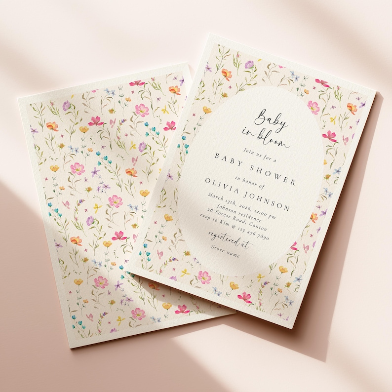 May include: Baby shower invitations with a floral design. The invitations feature a cream background with colorful watercolor flowers. The text "Baby in bloom" is displayed, along with event details for Olivia Johnson.
