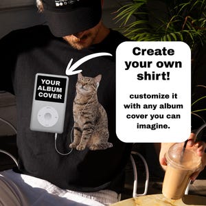 Könnte beinhalten: Schwarzes T-Shirt mit einer Grafik einer Katze mit Kopfhörern, einem digitalen Musikplayer und dem Text "YOUR ALBUM COVER". Das Shirt hat auch den Text "Create your own shirt! customize it with any album cover you can imagine."