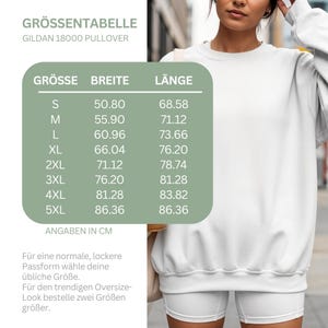 May include: A white Gildan 18000 pullover sweatshirt paired with white shorts. A green chart displays a size guide with columns for size, width, and length in centimeters, ranging from S to 5XL, with measurements from 50.80 to 86.36.