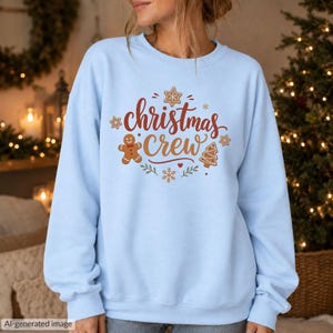 May include: A light blue long-sleeve sweatshirt featuring the text "christmas Crew" in red and brown script. The design includes a brown gingerbread man, a brown Christmas tree, and several small brown stars and snowflakes.