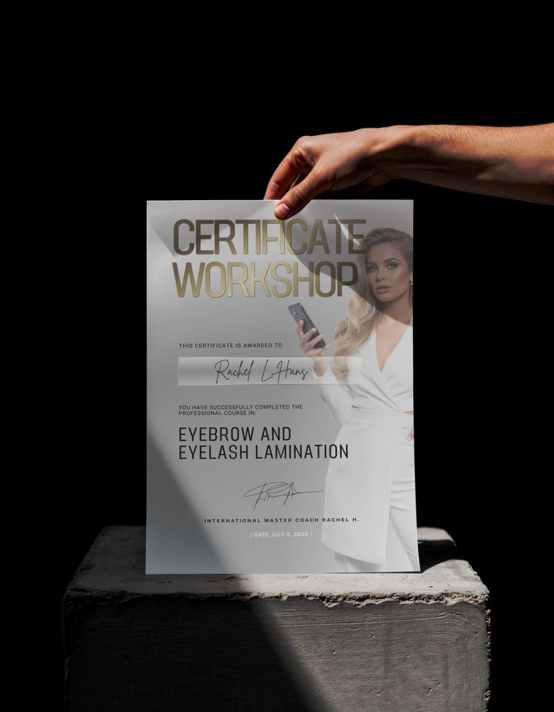 May include: A certificate with gold lettering that reads "CERTIFICATE WORKSHOP" and "EYEBROW AND EYELASH LAMINATION." The certificate is held by a hand and features a photo of a woman. The certificate is awarded to Rachel L. Hans.