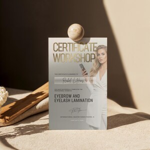 May include: A certificate with gold lettering that reads "CERTIFICATE WORKSHOP" and "EYEBROW AND EYELASH LAMINATION." The certificate is awarded to "Rachel L. Hans." A woman in a white dress is pictured on the certificate.