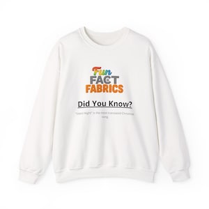Op de afbeelding: Witte sweatshirt met de tekst "Fun Fact Fabrics" in kleurrijke letters. Daaronder staat "Did You Know?" en een uitspraak over "Stille Nacht" als het meest vertaalde kerstlied.