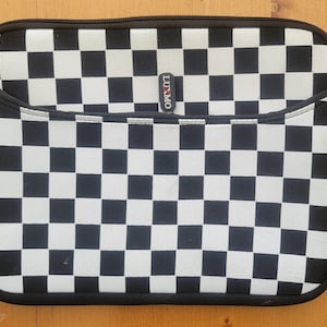 May include: Black and white checkered laptop sleeve with a zippered pocket and black trim. The sleeve has the brand name "LUXMO" on a small tag. The zipper pulls also have the brand name on them.