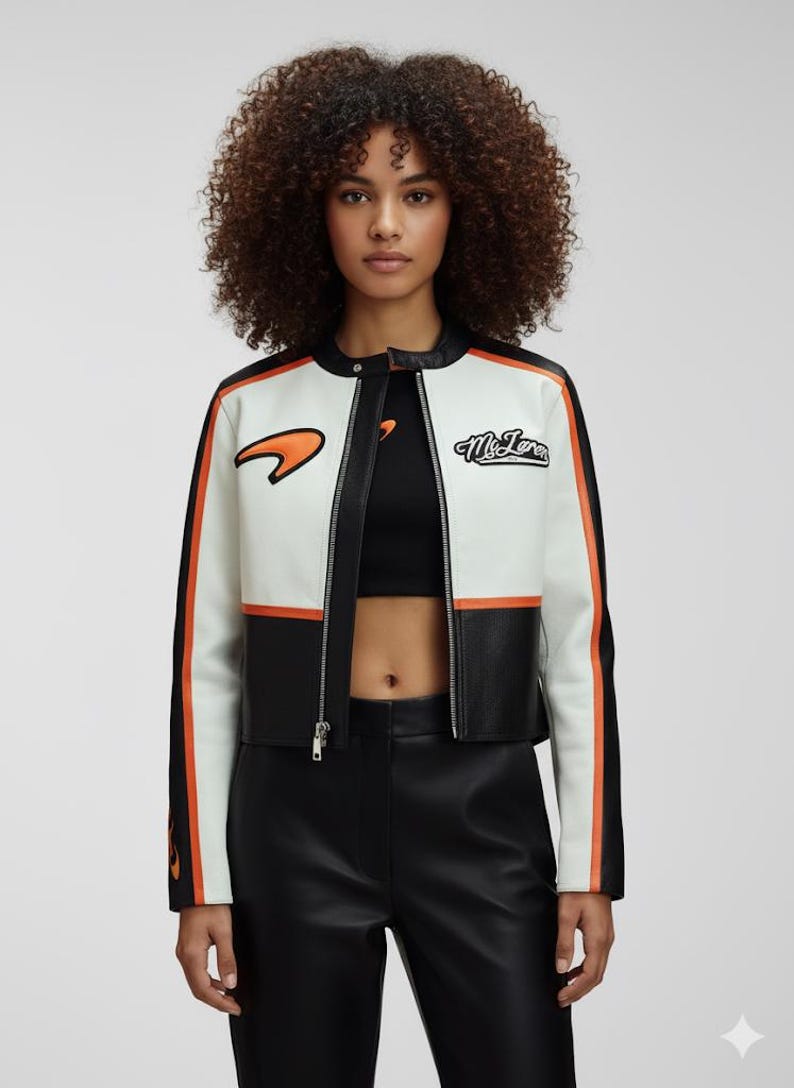 May include: White, black, and orange racing jacket with a zip-up front. The jacket has black sleeves with orange stripes and the McLaren logo on the chest. The jacket is cropped and made of leather.