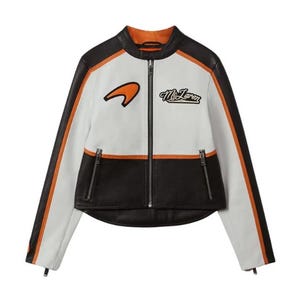 May include: A white, black, and orange racing jacket with a zip-up front. The jacket features the McLaren logo and text on the chest, with orange stripes down the sleeves. The jacket has a stand-up collar and two zip pockets.