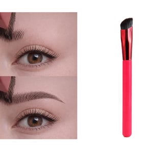 May include: A vibrant pink handled angled makeup brush with a black brush head. The image also shows an eye with shaped eyebrows, demonstrating the brush's use in eyebrow shaping and makeup application.