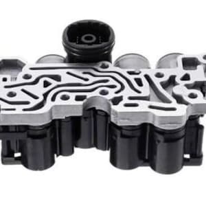 Puede incluir: Una pieza automotriz plateada y negra con un diseño complejo y estampado. La pieza tiene forma rectangular con múltiples componentes cilíndricos y un sistema de canales central e intrincado. El fondo es blanco liso.