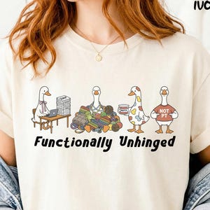 Könnte beinhalten: Elfenbeinfarbenes T-Shirt mit einer skurrilen Illustration von vier Gänsen in verschiedenen Szenarien. Der Text "Functionally Unhinged" ist unterhalb der Gänse aufgedruckt. Die Gänse sind mit verschiedenen Accessoires und Mustern dargestellt.