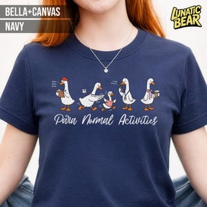 Puede incluir: Camiseta azul marino con una ilustración caprichosa de gansos realizando diversas actividades. La frase "Para Normal Activities" está impresa debajo. La camiseta está hecha de material Bella+Canvas y presenta el logotipo de Lunatic Bear.
