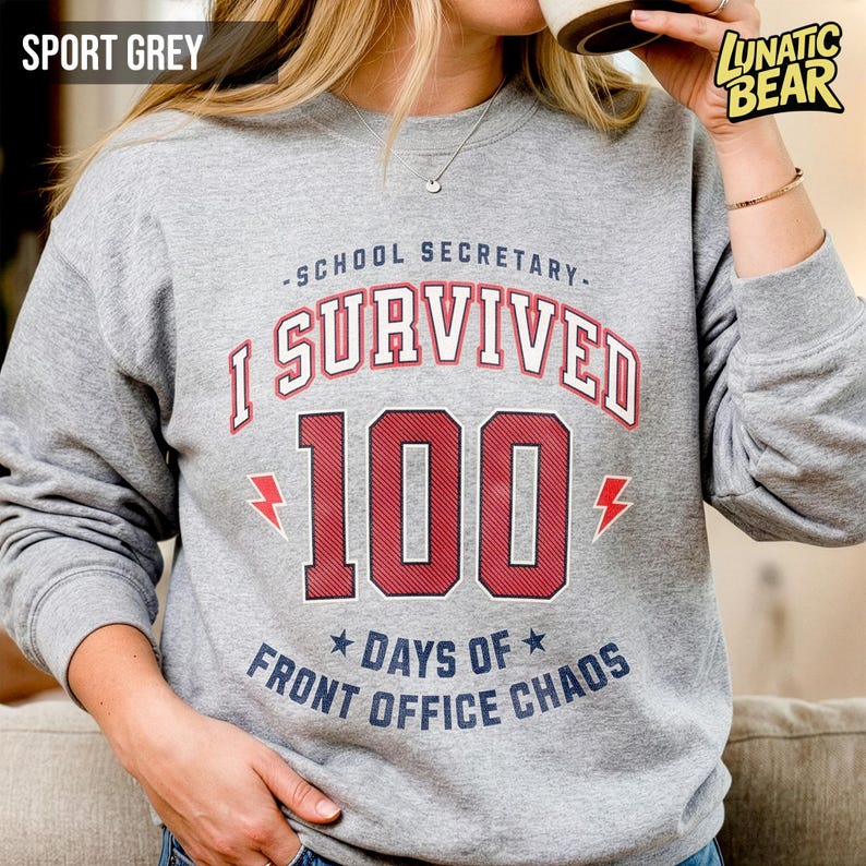 May include: Sport grey sweatshirt with the text "-SCHOOL SECRETARY- I SURVIVED 100 DAYS OF FRONT OFFICE CHAOS" in red and blue. The number 100 is in a bold, collegiate style font. Two red lightning bolts flank the number.