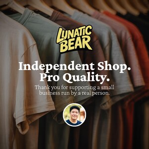 May include: A row of t-shirts in various colors, including beige, green, gray, and red, hanging on wooden hangers. The image features the text "LUNATIC BEAR" and "Independent Shop. Pro Quality."