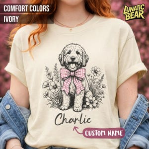 May include: A white ceramic mug with a black handle and the text "But First, Coffee" in a bold, black font. The mug is filled with a dark liquid, likely coffee, and sits on a light-colored surface.