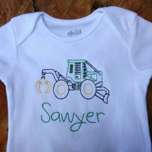 May include: White baby onesie with green embroidery of a green and yellow construction vehicle and the name "Sawyer" underneath.