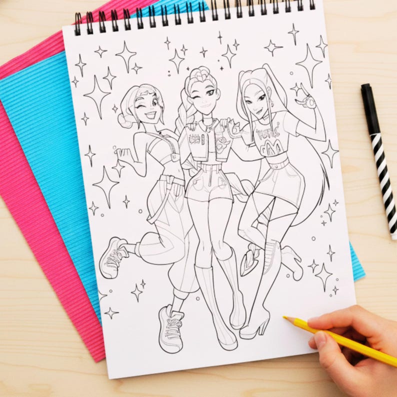 May include: A spiral-bound coloring book featuring a black and white illustration of three stylized female figures. The figures are surrounded by star-shaped designs. A hand holds a yellow colored pencil, ready to color the image. Pink and blue paper is visible.