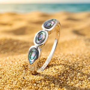 May include: A silver-toned ring featuring three oval-shaped, iridescent abalone shell inlays arranged vertically along the band. The shell pieces display swirling patterns of green, purple, and blue hues set within a polished metal frame.